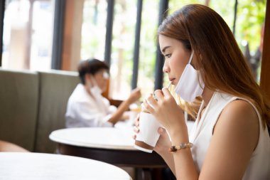 İnsanlar yüz maskesi kullanıyor, restoranda ya da kafede yüz maskesi takıyor, halka açık yerlerde enfeksiyon koruması uyguluyor.