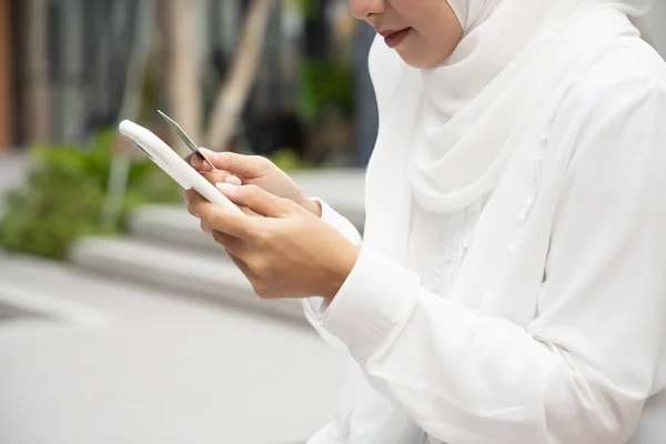 happy smiling Islamic muslim woman using smartphone and credit card for online shopping, electronic transaction; e-commerce, communication technology, data protection, transaction security concept