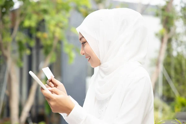 快乐微笑的伊斯兰穆斯林妇女使用智能手机和信用卡进行网上购物 电子交易 电子商务 通信技术 数据保护 交易安全概念 — 图库照片