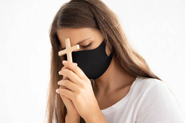 religious christian woman wearing face mask, mouth and nose covering during COVID-19 pandemic; concept of health care, social distancing, social responsibility, love and care to other people