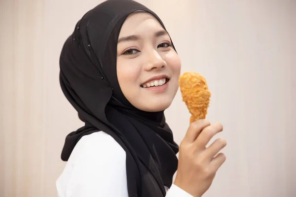 饥饿的伊斯兰妇女 吃着清淡的炸鸡鸡腿 美味的清真食品 医疗保健 饮食习惯 脆而美味的炸鸡汉堡 亚洲穆斯林妇女模型 — 图库照片