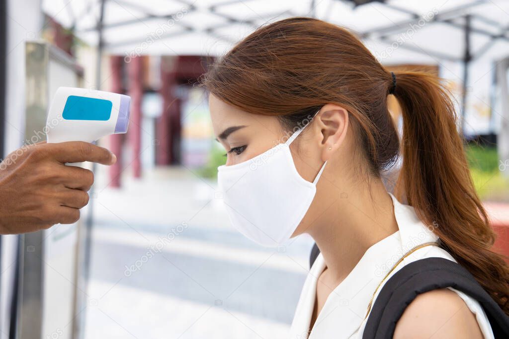 woman wearing face mask getting infrared thermal scanned for fever at check point