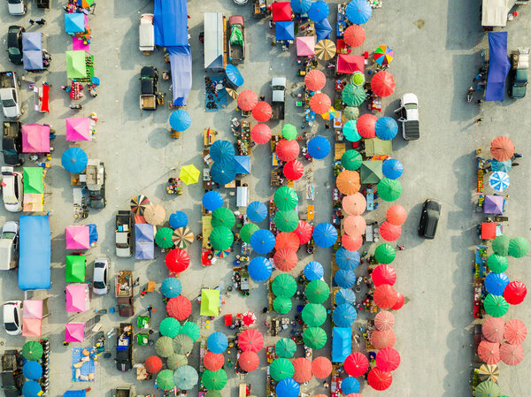 Вид с воздуха с камеры дрона блошиного рынка с красочными зонтами и палатками под вечерним солнцем, Таиланд
