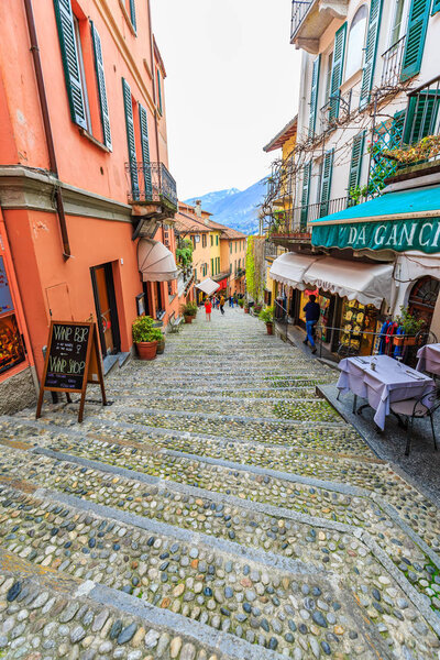 BELLAGIO, ITALY - 15 APRIL 2018 - Slope alley between picturesque shops and restaurants consists of many steps that lead to the lakefront of Lake Como