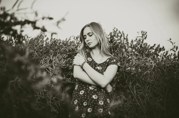 Una joven rubia europea delgada chica se encuentra en medio de una planta muy alta de color púrpura y amapola —  Fotos de Stock