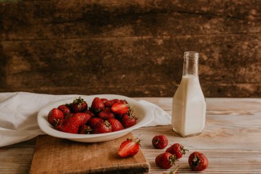 Masanın üzerine taze sulu kırmızı çilekler ve kaliteli kalaslar serpiştirdim. Nane yaprağı. Damlalar ve dökülen sütler. Sebze kesme tahtası. Yüksek kalite fotoğraf