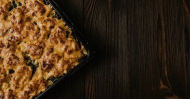 Köfteli pizza. Fırında pişmiş et, siyah metal bir pişirme tepsisinin üzerinde yatıyor. Ağız sulandıran peynir sosu. 