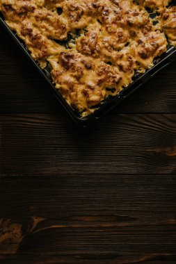 Köfteli pizza. Fırında pişmiş et, siyah metal bir pişirme tepsisinin üzerinde yatıyor. Ağız sulandıran peynir sosu. 