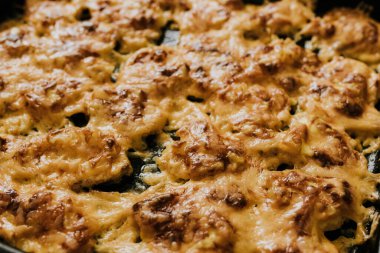 Köfteli pizza. Fırında pişmiş et, siyah metal bir pişirme tepsisinin üzerinde yatıyor. Ağız sulandıran peynir sosu. 