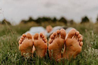 Kadın ve erkeğin ayakları. Bir adamın ayakları ve çimlerin üzerinde bir kız. Yazın parkta aile pikniği, çimenleri biçmek değil..