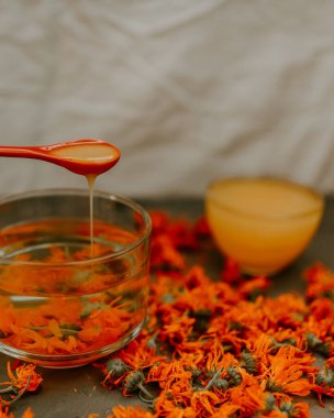 Bir kadının eli kaşıktan fincana bal döker.