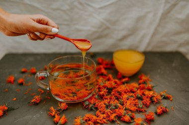 Bir kadının eli kaşıktan fincana bal döker.