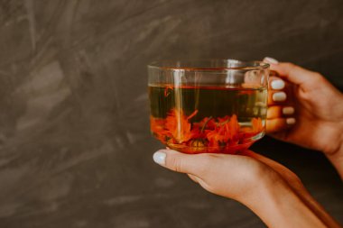 Kadife çiçeğinden çay, kadın elinde portakal takvimi.