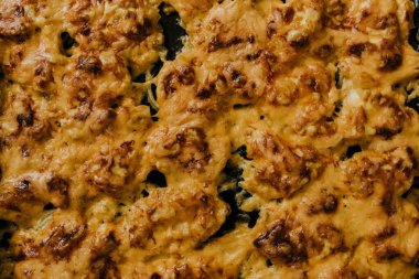 Köfteli pizza. Fırında pişmiş et, siyah metal bir yemek tepsisinin üzerinde yatıyor.