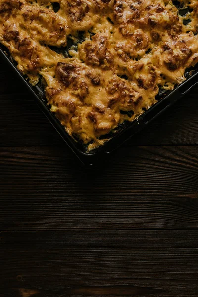 Meat cheese pizza. Baked meat in the oven lies on a black metal baking sheet — Stock Photo, Image