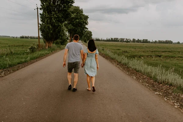 Mladý pár muž a žena jdou držet za ruce podél cesty — Stock fotografie