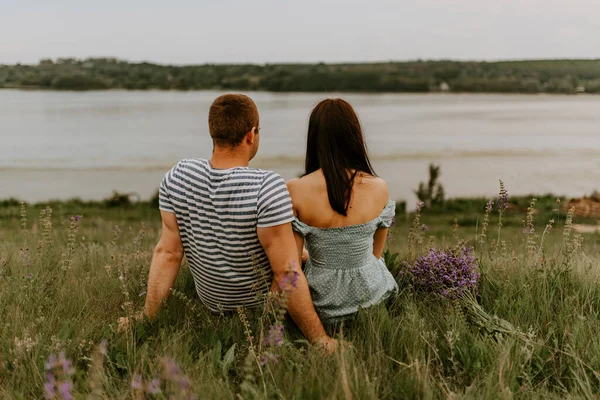 Genç kadın ve adam nehrin kıyısında oturuyorlar. — Stok fotoğraf