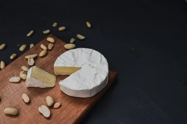 Сыр камамбер с плесенью и орехами на деревянной доске — стоковое фото
