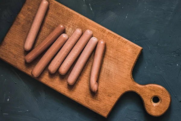 Boiled fried sausages sausages lie on a wooden kitchen board — Stock Photo, Image