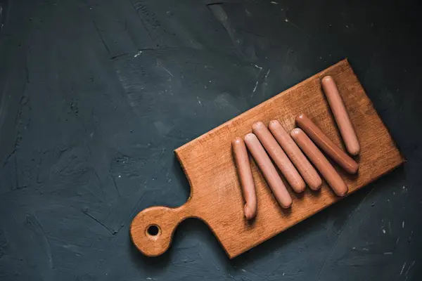 Gotowane kiełbaski smażone leżą na drewnianej desce kuchennej — Zdjęcie stockowe