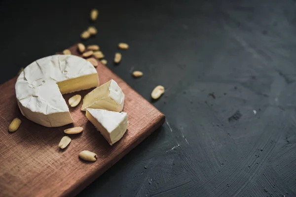 Cheese camembert with mold and nuts on wooden board — Stock Photo, Image