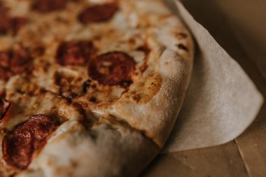 Peynirli ve salamlı bir pizza karton bir kutunun üzerinde duruyor.