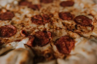 Peynirli ve salamlı bir pizza karton bir kutunun üzerinde duruyor.