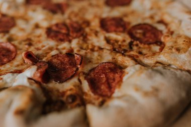 Peynirli ve salamlı bir pizza karton bir kutunun üzerinde duruyor.