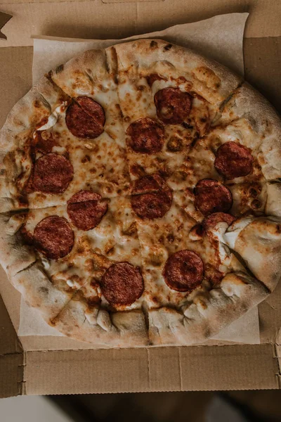 Una pizza con formaggio e salame si trova su una scatola di cartone — Foto Stock