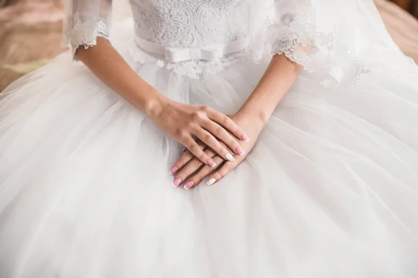 As mãos femininas da noiva de pele clara jazem no vestido de casamento branco — Fotografia de Stock