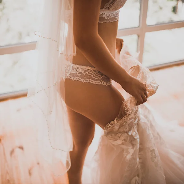 European skinny bride in lingerie puts on a wedding dress — Stock Photo, Image