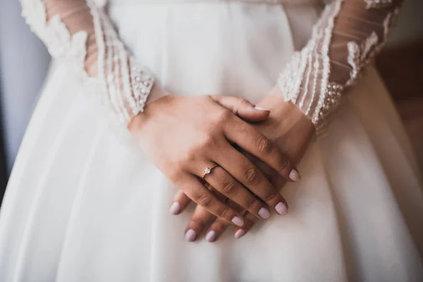 As mãos femininas da noiva de pele clara jazem no vestido de casamento branco — Fotografia de Stock