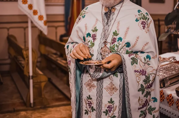 Священник в белой одежде держит блюдце с золотыми кольцами. — стоковое фото