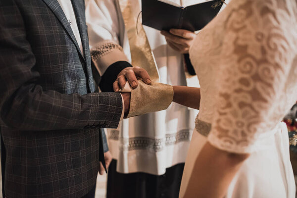 The priest covered the hands of the newlyweds and blessed.