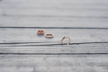 Gelin ve damadın alyansları tahta arka planda.