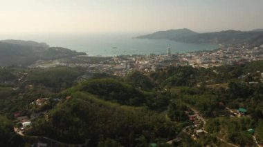 İnsansız hava aracı gün batımından sonra orman ve deniz üzerinde uçuyor.
