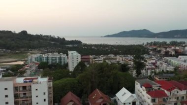 İnsansız hava aracı gün batımından sonra orman ve deniz üzerinde uçuyor.
