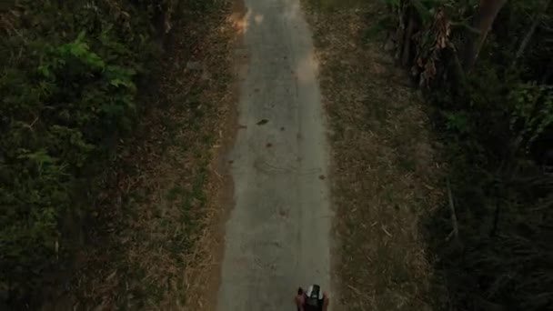 Mulher de moto capacete caminha ao longo da estrada no meio da selva escura verde — Vídeo de Stock