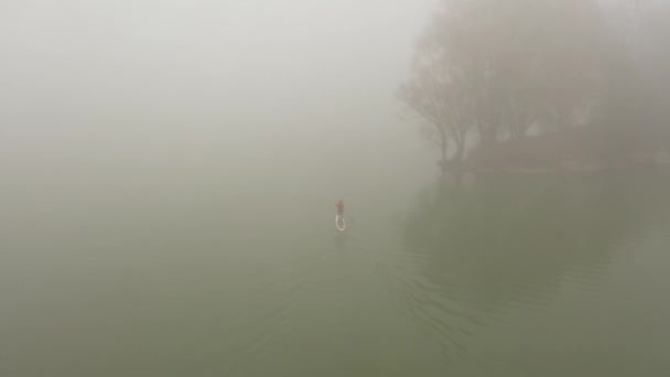 Один человек плавает на доске на реке в очень густом тумане — стоковое видео