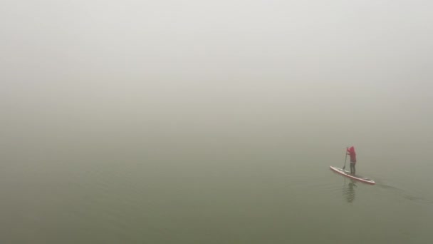 Un uomo solo galleggia su una tavola su un fiume in una nebbia molto fitta — Video Stock