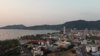 İnsansız hava aracı gün batımından sonra orman ve deniz üzerinde uçuyor.