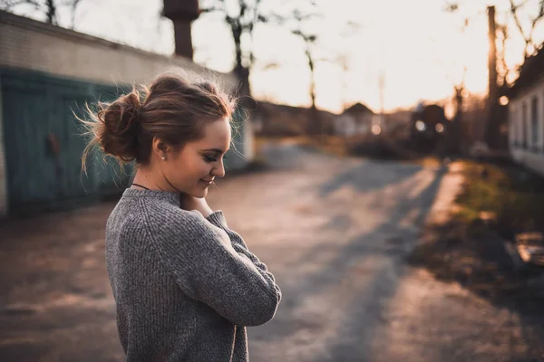 Mujer con el pelo atado en un moño en suéter de punto gris en la puesta del sol — Foto de Stock