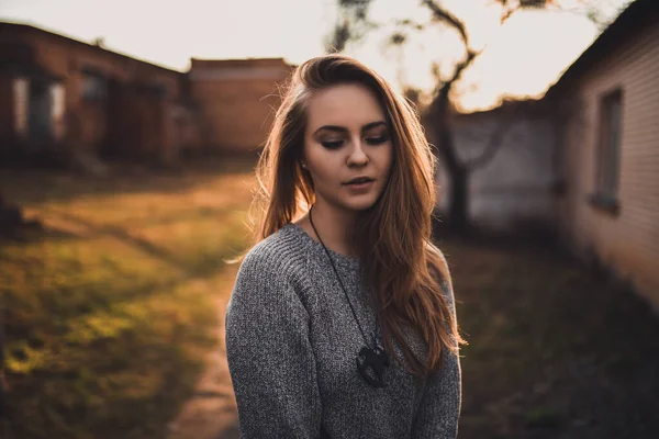 Mujer en suéter de punto gris. colgante de madera en el cuello en forma de caballo al atardecer — Foto de Stock