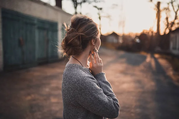 woman with hair tied in a bun in gray knitted sweater On the Sunset