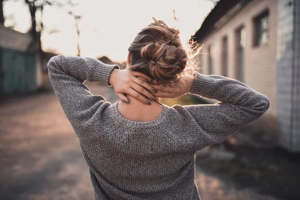 woman with hair tied in a bun in gray knitted sweater On the Sunset