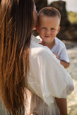 Anne gök mavisi denizde yürüyor ve oğlunu kollarında taşıyor.