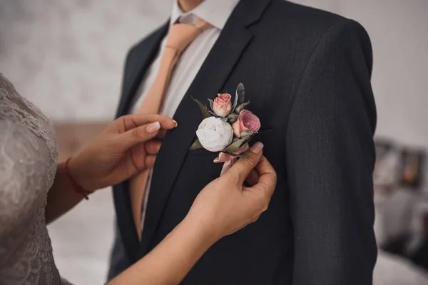 Mariée attache une boutonnière à un homme en veste noire — Photo