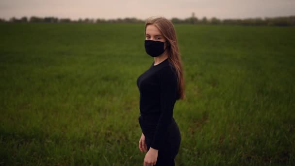 Una donna in maschera nera cade lentamente sul terreno erboso verde pandemia covid-19 Coronavirus — Video Stock