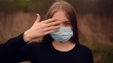 Tıbbi maskeli bir kadın ellerini kapatır ve elleri ile yüzünü açar. Salgın Covid-19 Coronavirus. 