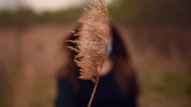 Tıbbi maskeli kadın yüzünü kuru kamış salgını salgını ile kaplıyor.